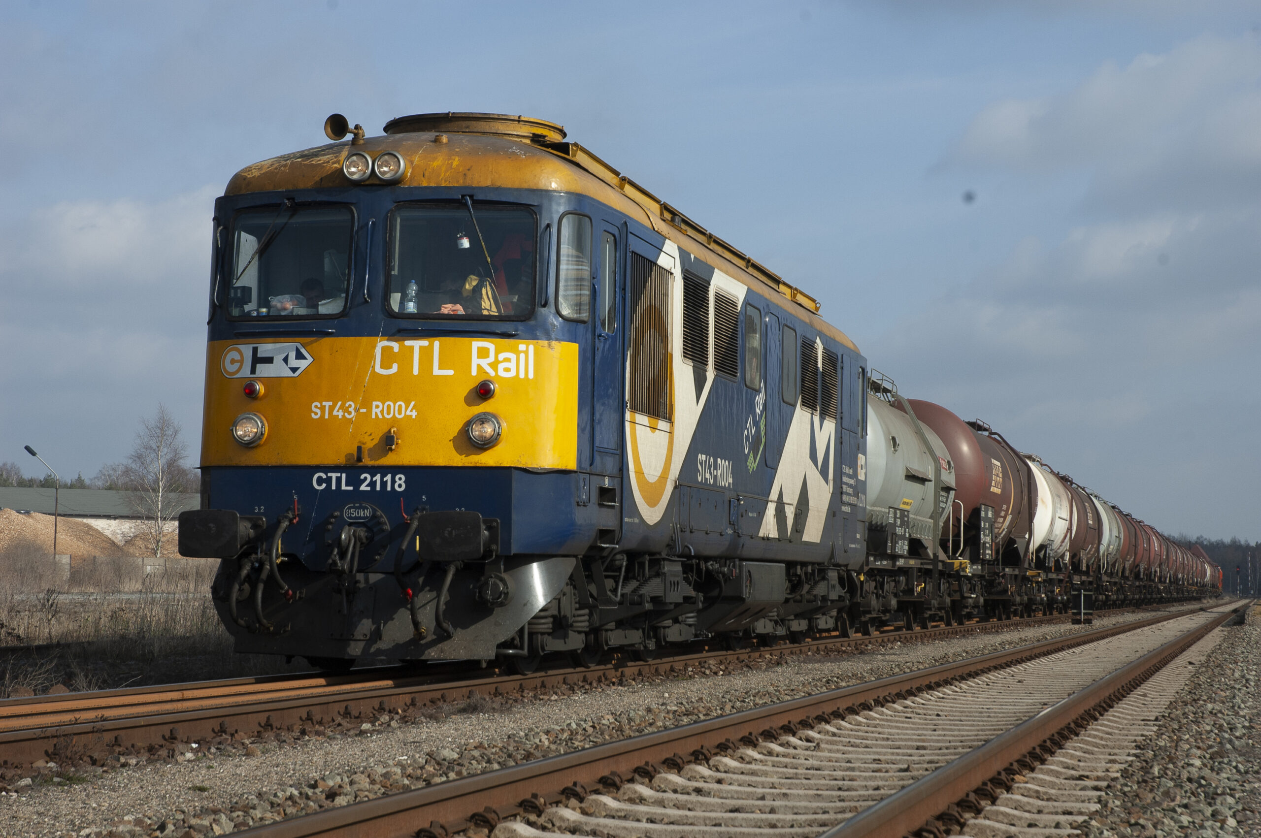 Die blau-gelbe Lok CTL 2118 vor einem langen Kesselwagenzug